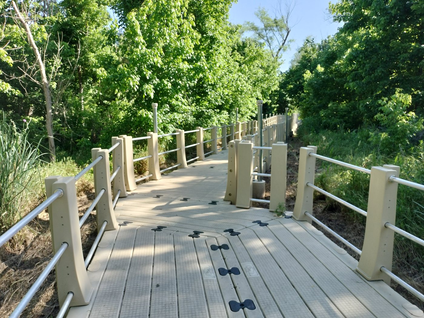 A wide wooden boardwalk over marsh grass at Lake Weatherford, Texas, under a hazy sky.